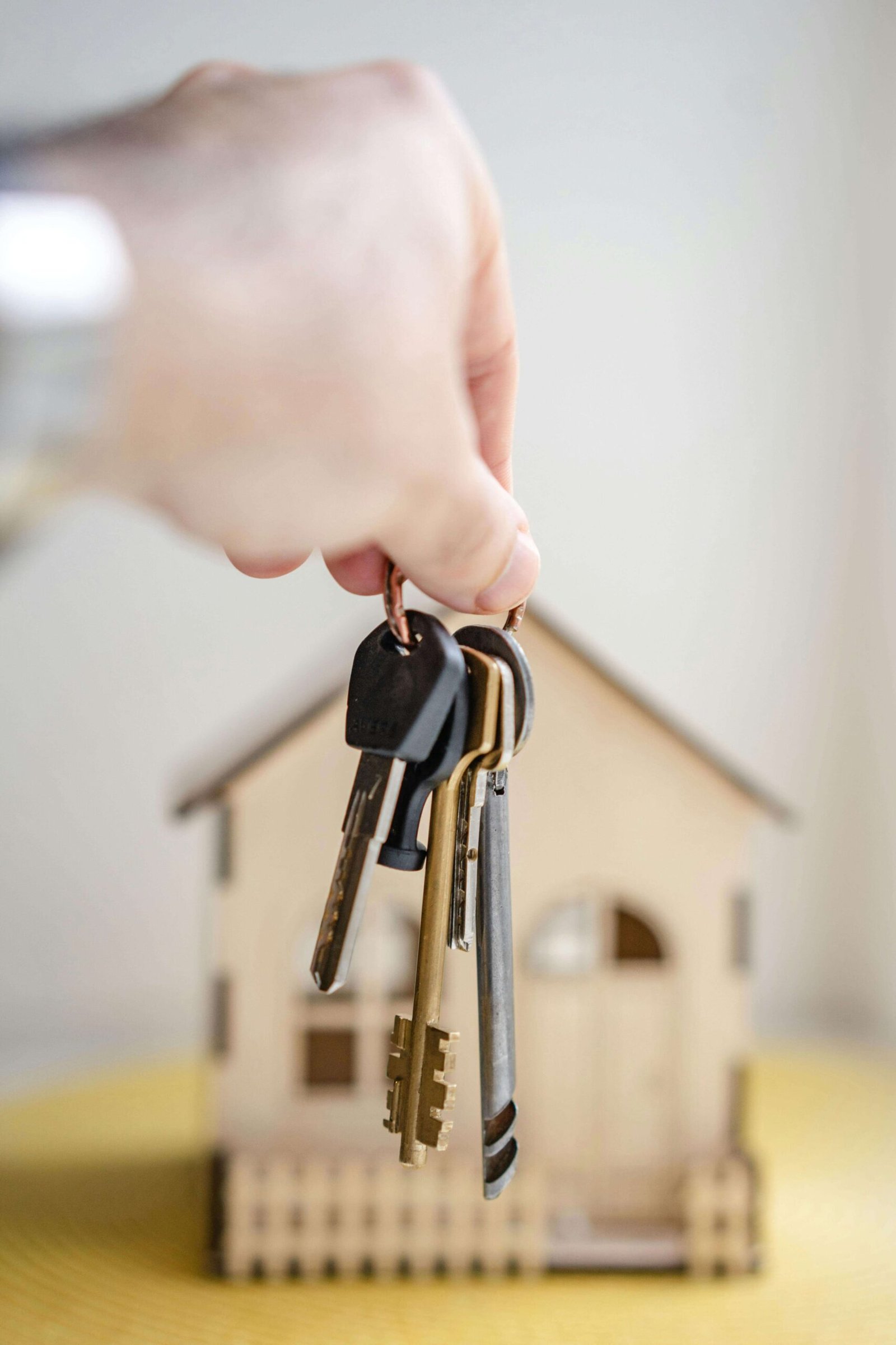 Image; hand holding a key in front of miniature house. To give a message of getting a new house.